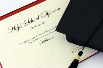 A photo of a high school diploma with a graduation cap laying on top of it.